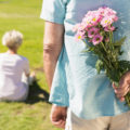 Senior,Man,Hiding,Flowers,Behind,His,Back,On,A,Sunny