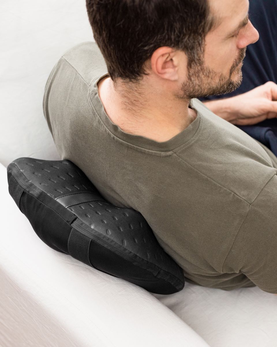 Eine Person nutzt ein Medisana Massagekissen im unteren Rückenbereich zur Lockerung verspannter Muskeln.