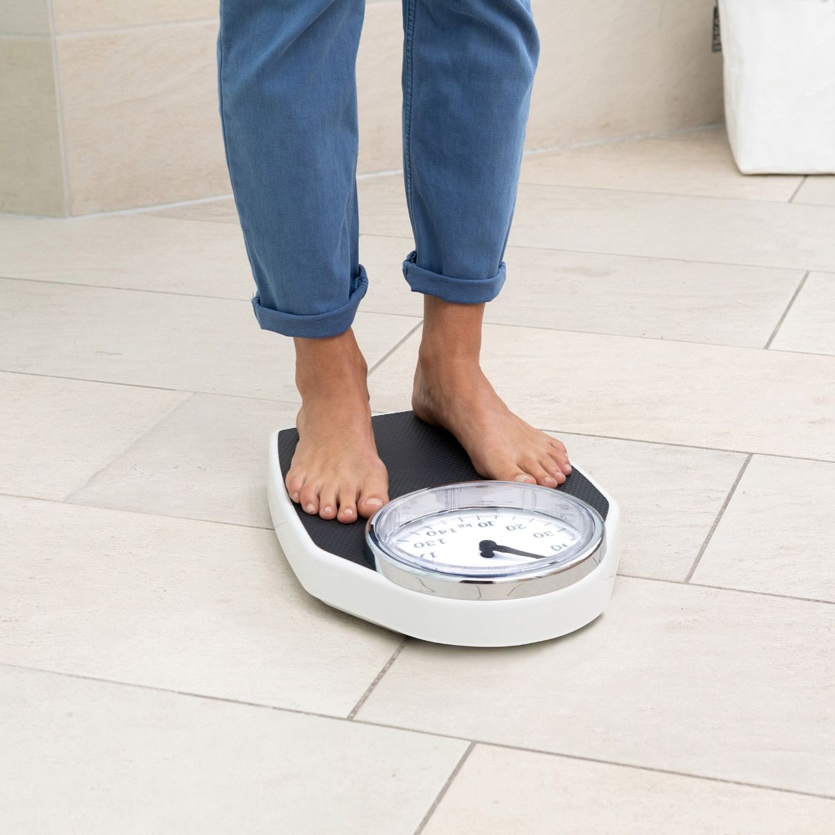 Füße einer Person auf einer klassischen analogen Personenwaage mit großem Runddisplay.